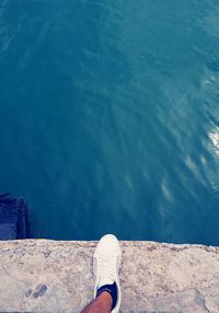 Low section of person in swimming pool against sea