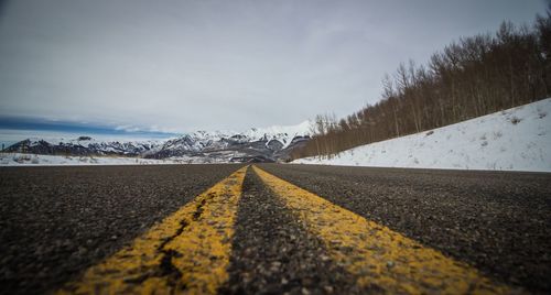 Surface level of road amidst snowcapped mountains against sky