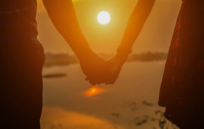 Silhouette man standing against orange sky during sunset