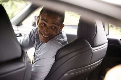 Happy man looking back over shoulder while sitting in car