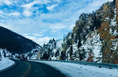 Road by trees against sky during winter