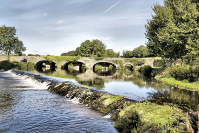 Arch bridge over river against sky