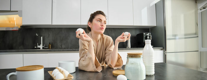 Portrait of smiling young woman sitting in kitchen