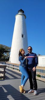 Friends with arms outstretched against built structure