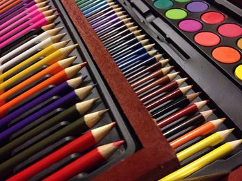 High angle view of colored pencils and watercolor palette