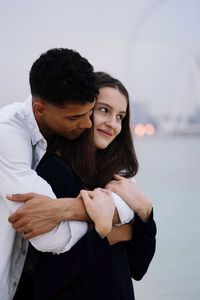 Portrait of smiling young couple standing against sky