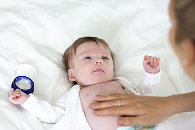 Cropped hand of woman applying cream on son belly 