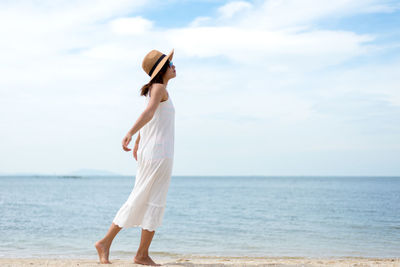 Woman standing by sea against sky