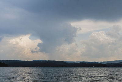 Scenic view of sea and mountains against cloudy sky