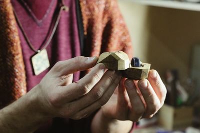 Midsection of woman holding ring in wooden box