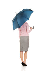 Rear view of woman with umbrella standing against white background