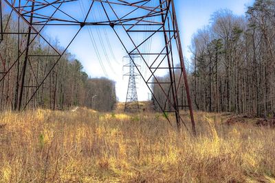 Electricity pylon on field against sky