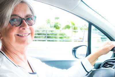 Portrait of smiling senior woman in car
