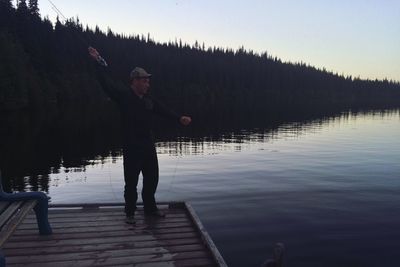 Man standing on pier while fishing in logan lake