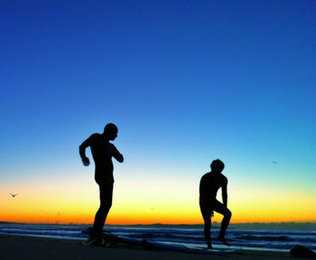 Silhouette people on beach at sunset