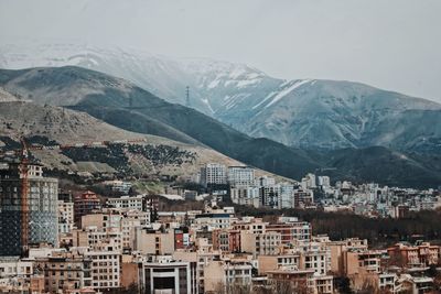 Aerial view of townscape and mountains against sky