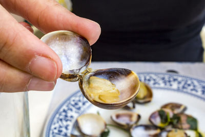 Close-up of woman hands eating clams