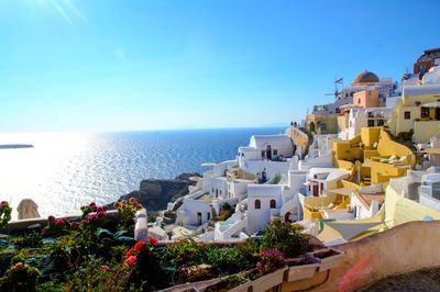 Buildings by sea against clear blue sky