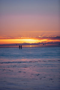 Silhouette people on beach against sky during sunset