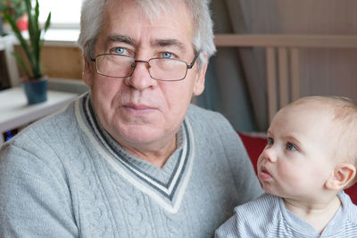 Elderly man and baby girl. happy old man holds a little child on hands. grandchild and grandfather. 