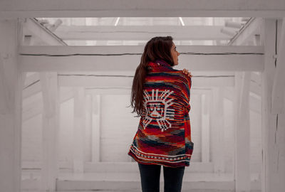 Young woman standing against white wall