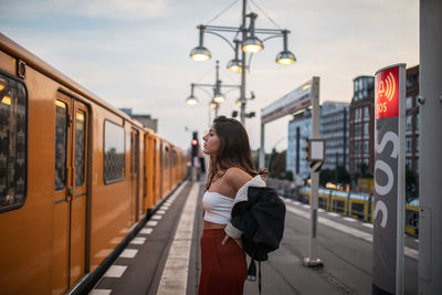 Side view of woman standing on train at railroad station