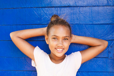 Portrait of smiling girl against blue wall
