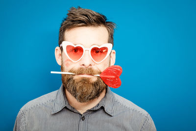 Portrait of man wearing sunglasses against blue background