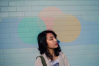 Beautiful young woman lying down against brick wall