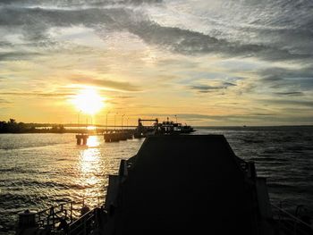 Silhouette pier over sea against sky during sunset