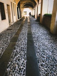 Rear view of man walking on footpath amidst buildings in city