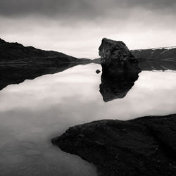 Scenic view of rocks by lake against sky