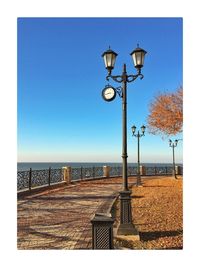 Street light by sea against clear blue sky