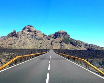 Road by mountain against blue sky