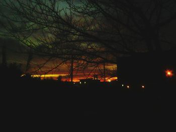 Silhouette of bare trees against sky at sunset