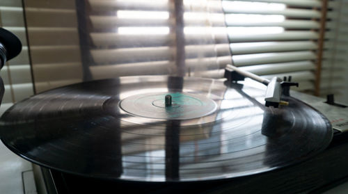 Close-up of record on turntable by window blinds at home
