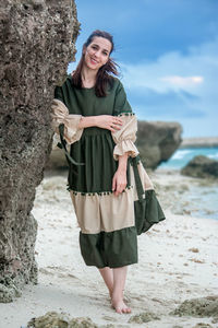 Portrait of young woman standing on rock at beach