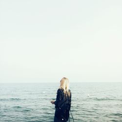 Scenic view of woman at sea against blue sky