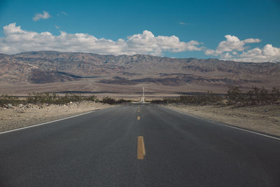 Road by mountains against sky