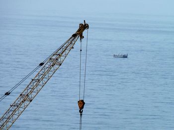 Fishing rod by sea against sky