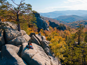 Rear view of man sitting on rock