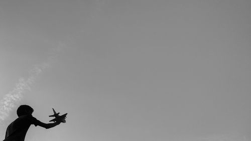 Low angle view of boy holding toy airplane against sky