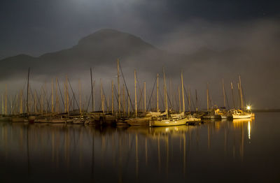 Sailboats moored in lake against sky