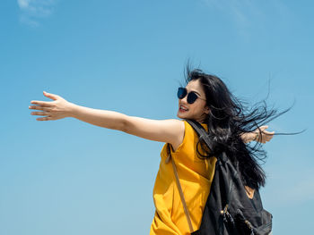 Woman wearing sunglasses standing against clear blue sky