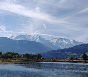 Scenic view of lake by snowcapped mountains against sky