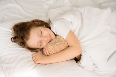 High angle view of girl sleeping on bed