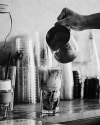 Cropped hand of man pouring milk in glass at marble