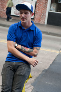 Full length of man holding camera while standing outdoors