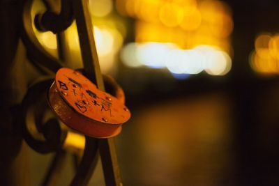 Close-up of love lock hanging in illuminated city at night