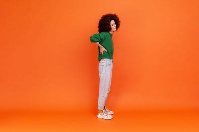 Rear view of woman standing against yellow background